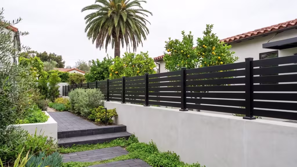 Black aluminum semi privacy wall topper crowning a light-gray concrete wall at a Mediterranean-style home