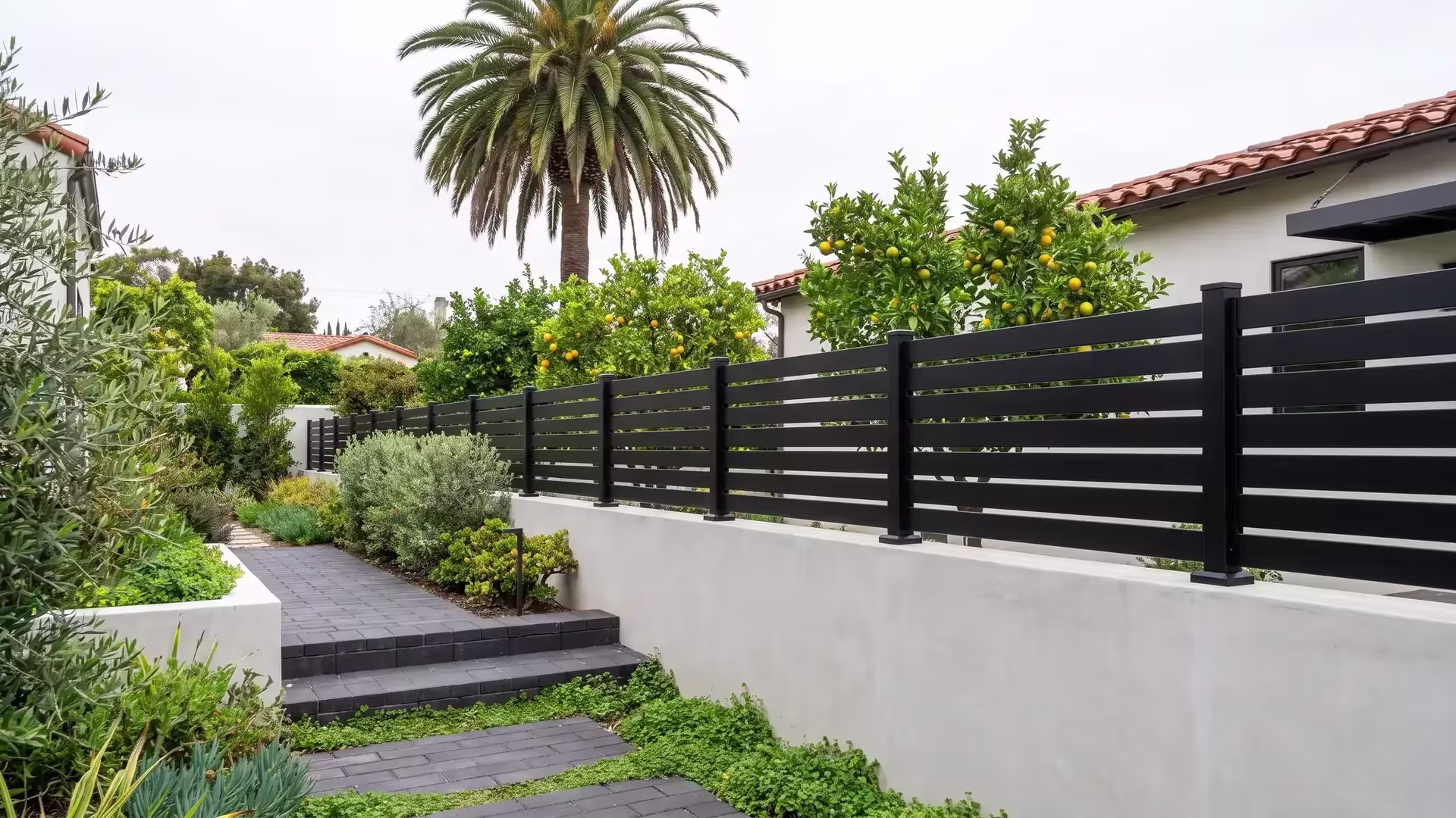 Black aluminum semi privacy wall topper crowning a light-gray concrete wall at a Mediterranean-style home